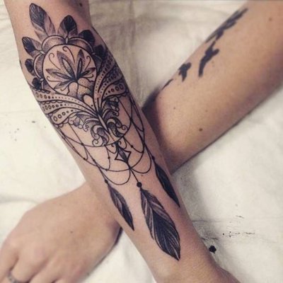 Tatouage plume avec un beau motif sur l'avant bras